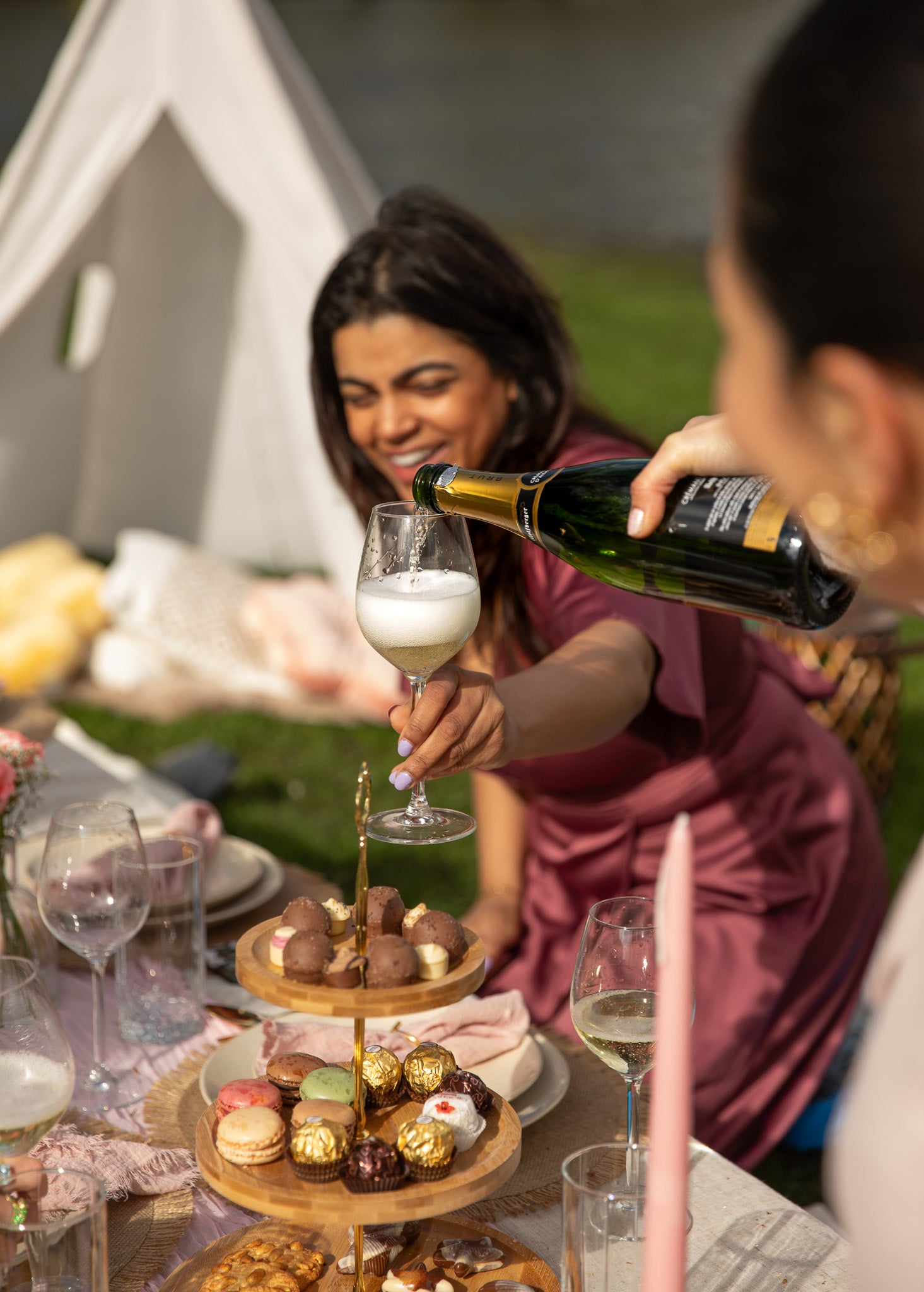girl pouring champagne at luxury picnic in park