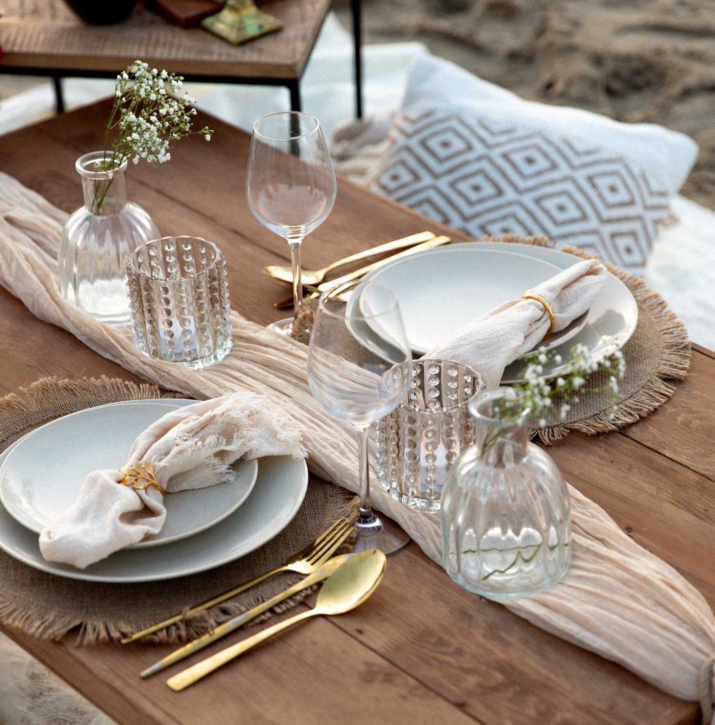 luxury wooden picnic table with plates, cutlery, glasses, table runner and napkings on the beach