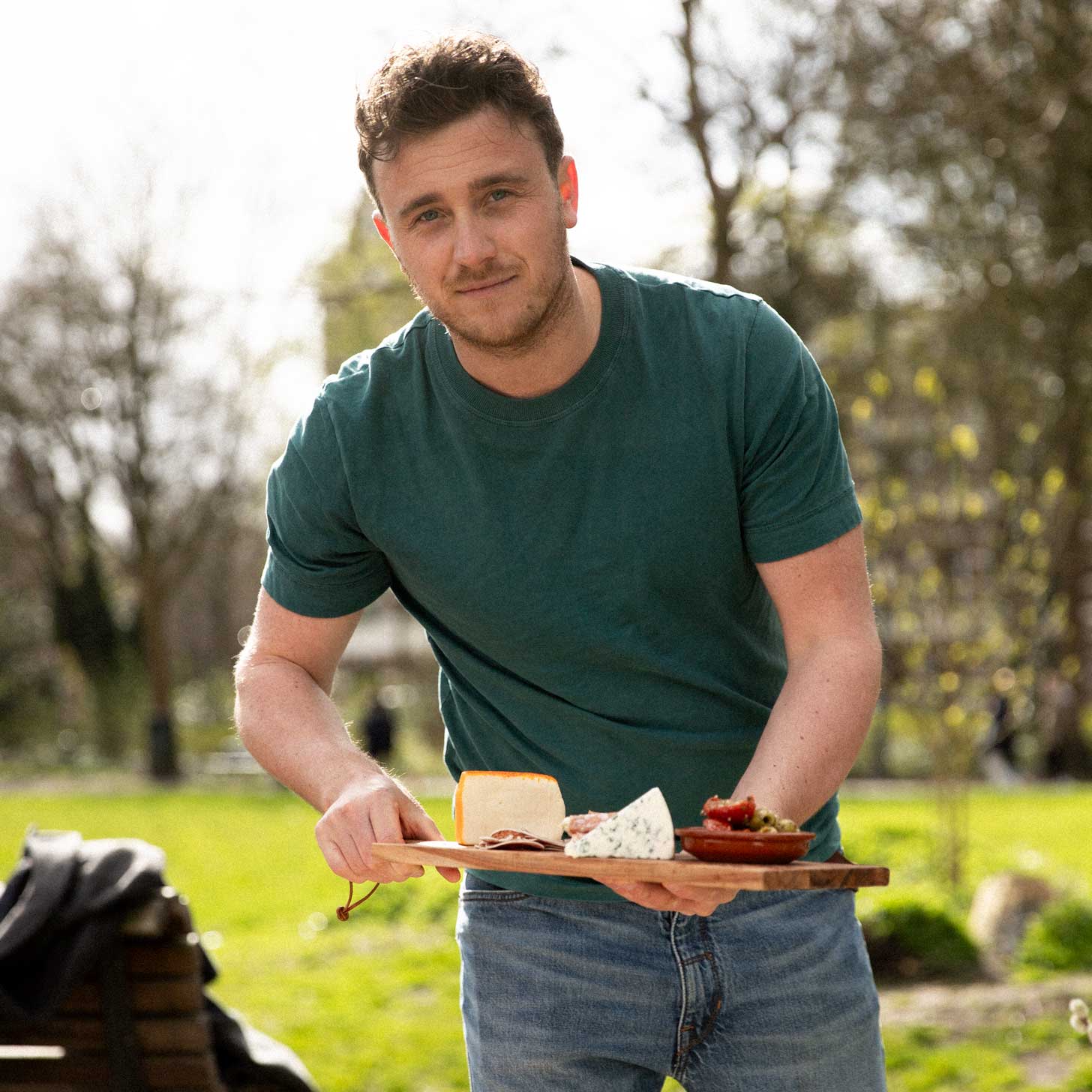 Chef with food board with cheese platter in park