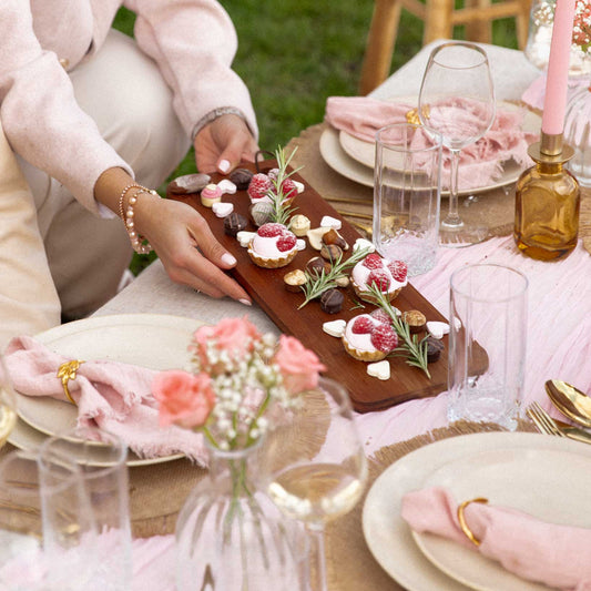 serving food board at luxury picnic in pink, with sweets and chocolates