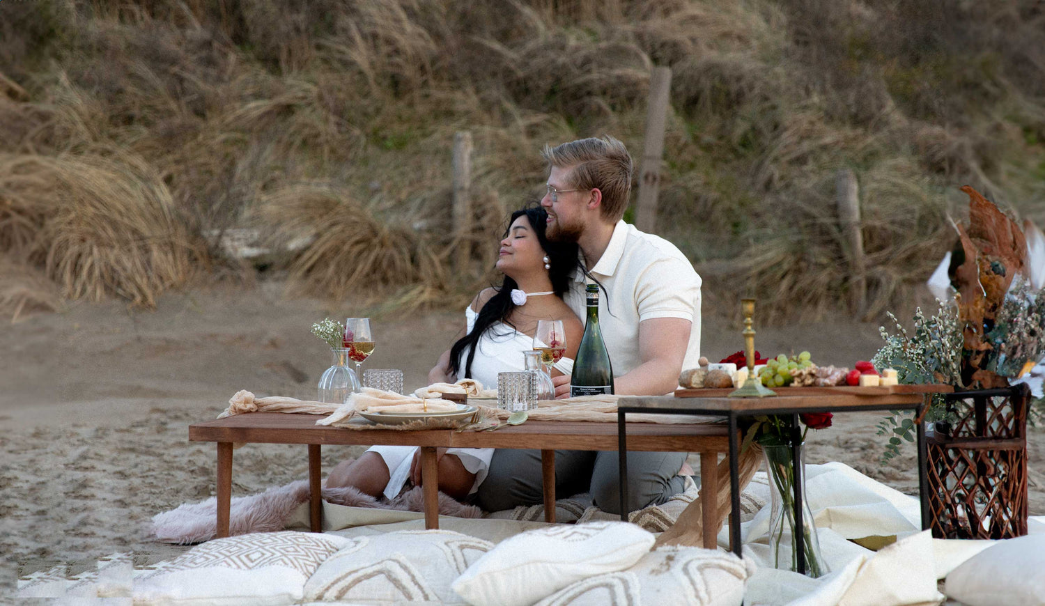 romantic couple at beach with luxury picnic date in wedding style, including food and drinks
